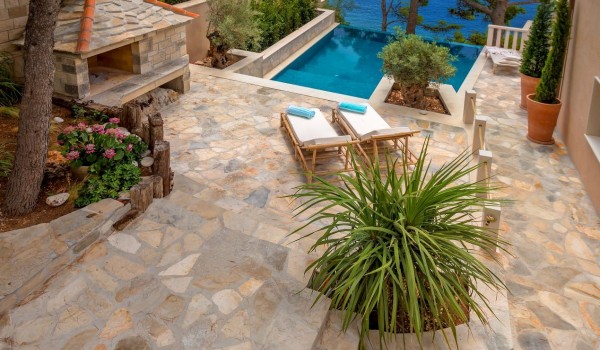 A view of the spacious pool next to which there is a fireplace and two deckchairs on the property of the luxury villa Bliss on the island of Brač