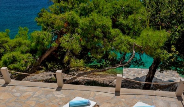 A spacious paved terrace with sun loungers overlooking a peaceful Mediterranean oasis