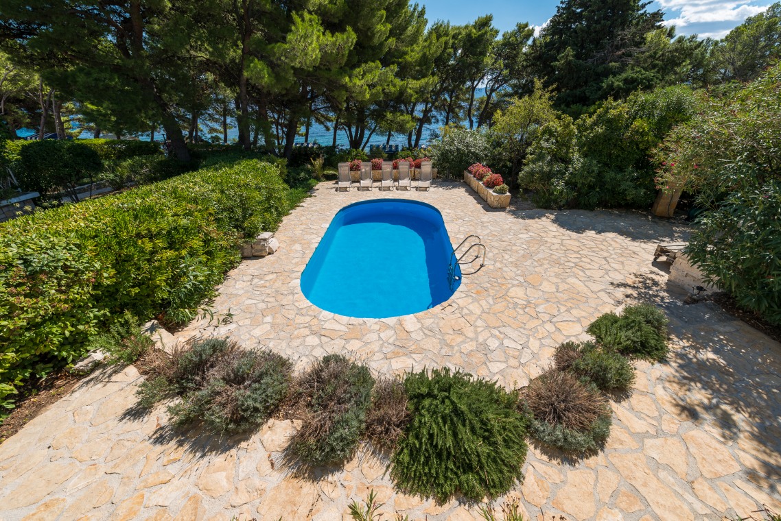 Vanjski privatni bazen s kamenim platoom u hrvatskoj luksuznoj vili Oasis na Braču uz more za odmor i najam.