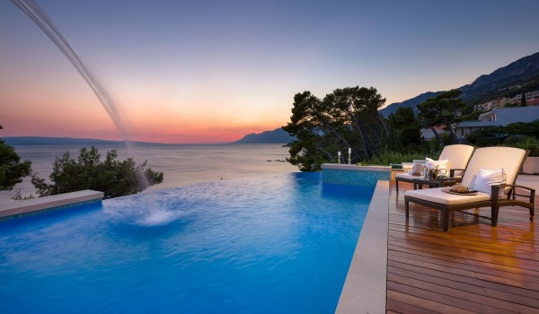 Private heated swimming pool with sunbeds in the fenced yard of the Croatia modern villa Brela Pride for rent and luxury vacation in Brela