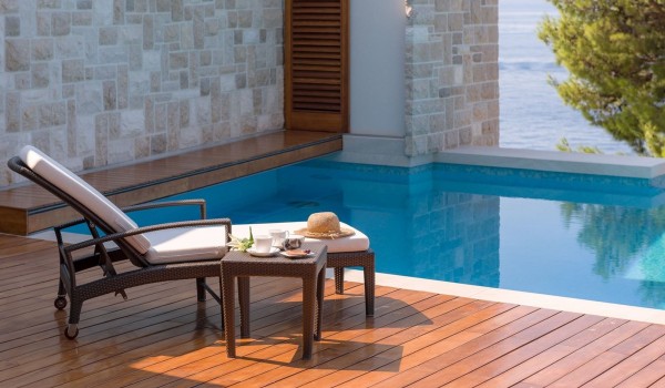 A drink served on the table next to a large heated swimming pool in an air-conditioned villa for rent and vacation in Brela