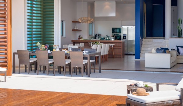 Modern interior of the living room with sofas, dining table and kitchen and terrace in a family holiday villa in Brela