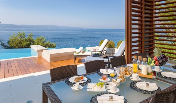 View from the dining room that opens onto a terrace with deckchairs and a heated pool with a beautiful view of the sea and the beach in Brela for 10 people