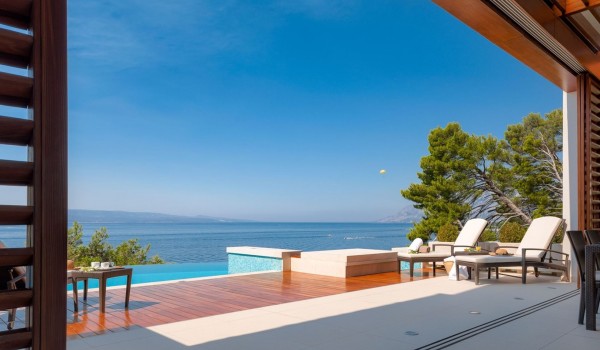A view of the beautiful sea and a terrace with a sunbed next to the heated swimming pool of a luxury family vacation villa by the beach in Brela