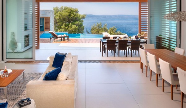 View from the air-conditioned living room to the terrace with a dining area of a private villa with a swimming pool in Brela