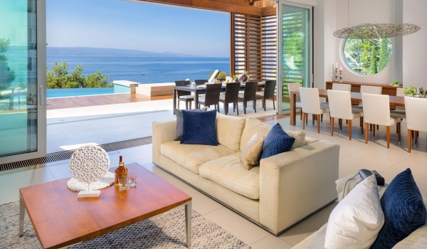Interior living area with comfortable furniture and dining area and access to the terrace with infinity pool of a luxury pet-friendly villa for rent and vacation in Brela