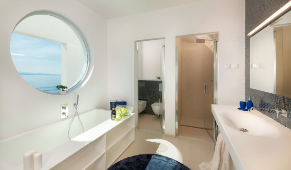 Elegantly decorated en-suite bathroom with toilet, bathtub, walk-in shower and sink in a luxury vacation villa with pool by the sea in Brela