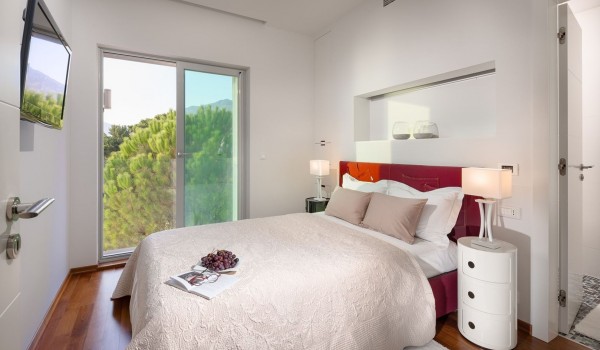 Elegantly decorated interior of an air-conditioned bedroom with a king size bed and SAT TV on the first floor of a luxury villa with a swimming pool for vacations Brela Pride in Brela