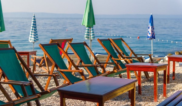 A beautiful pebble beach with sunbeds and umbrellas, safe for children in front of a luxury villa for rent and holiday by the sea in Brela