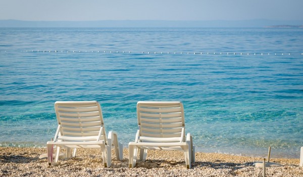 Beautiful blue sea in front of a pebble beach with sunbeds in Brela