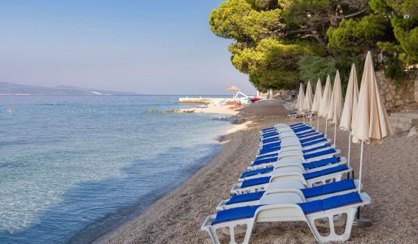 Swimming pool on the pebble beach in Brela, safe for children and adults, with deckchairs, umbrellas and showers