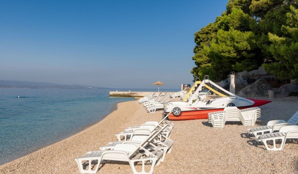 Beautiful clear sea next to a pebble beach with sunbeds and showers in Brela