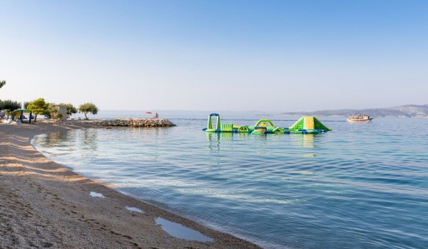 Pebble beach with a wonderful clear blue sea and a view of the aqua park safe for children and adults in Brela