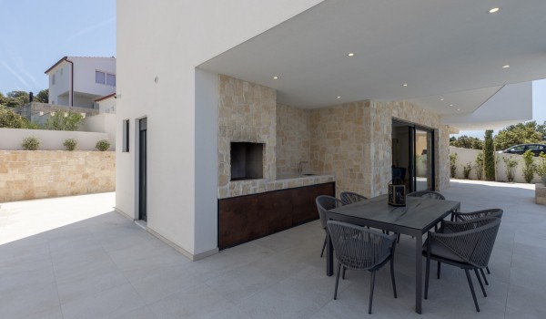 Outdoor private terrace of Croatia luxury villa with fireplace and dining table for family vacation