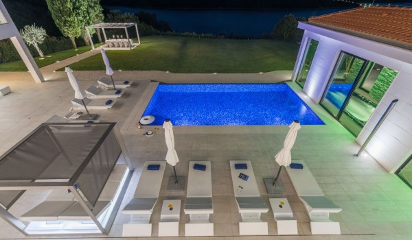 Night view of loungers by the pool of Croatia luxury seafront villa with private parking and sauna in Istria