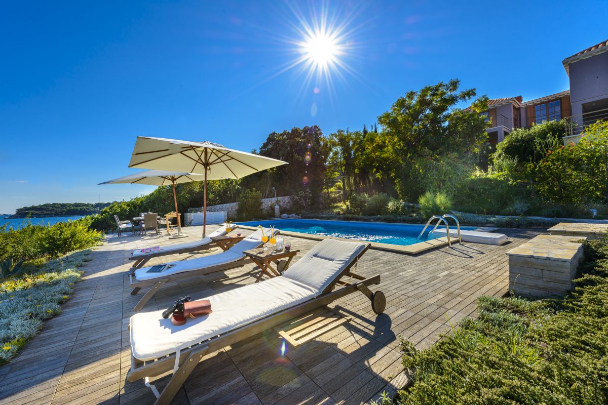 Sun loungers with parasols in front of the Croatia luxury beachfront villa Dubrovnik Escape with a gym and private sea deck right by the sea on Kolocep