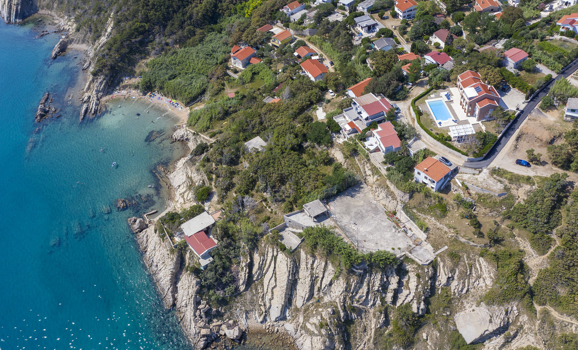 A view of the Croatia luxurious villa Exclusive Pag with a large property and swimming pool located by the sea and a pebble beach on the island of Pag in the town of Bošana