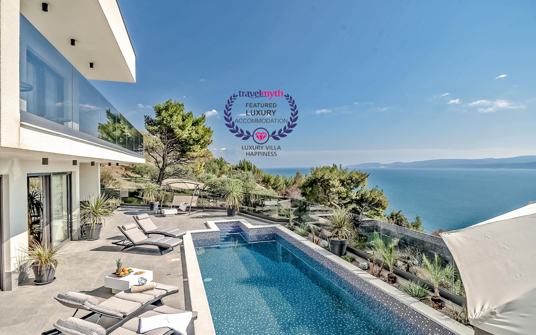Spacious fenced terrace with private pool surrounded by sun loungers and seaview from the property of the luxury villa Happiness