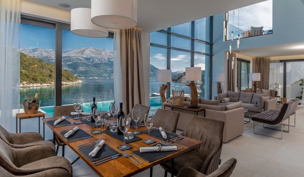 The interior of the luxury villa Korcula Prestige on the island of Korcula with a dining table set for 8 people and a living room with a sofa and armchairs