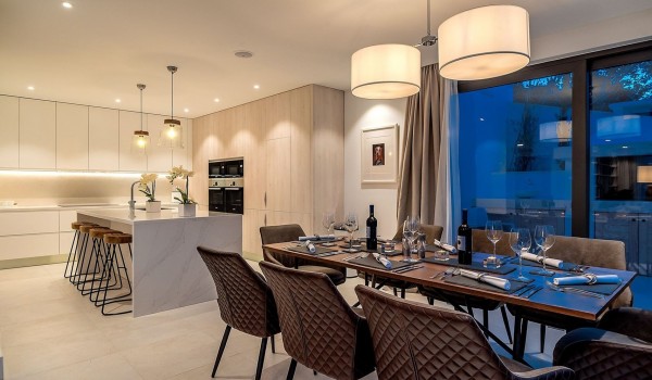 The interior of the luxury villa Korcula Prestige on the island of Korčula with a dining table and chairs, a kitchen and a kitchen island with high chairs