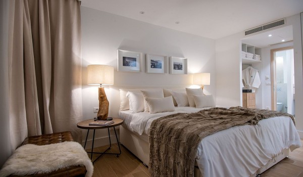 A bedroom with a comfortable double bed and a leather stool in the luxury villa Korcula Prestige on the island of Korcula