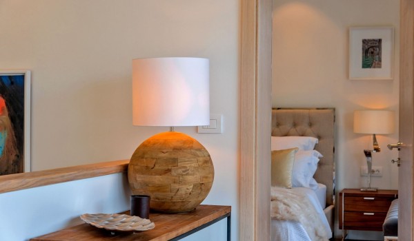 A view of a wooden table with a lamp and a double bed in the bedroom in the luxury villa Korcula Prestige on the island of Korcula