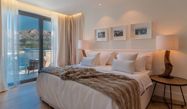 A bedroom with a comfortable double bed and its own exit to the outside terrace in the luxury villa Korcula Prestige on the island of Korčula