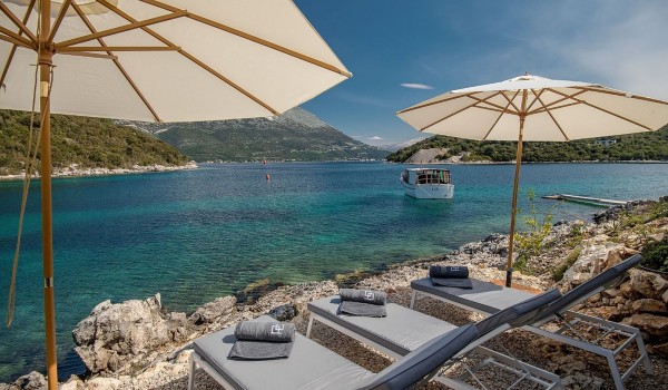 Sunbeds and umbrellas on the beach next to the luxury villa Korcula Prestige on the island of Korčula