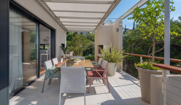 Outdoor dining are with hearth on roofed terrace in family Sutivan luxury holiday villa by the beach with private pool.