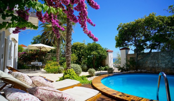 The entrance to the courtyard of the villa Beach House Orebic, decorated with greenery, and the outdoor pool surrounded by deckchairs