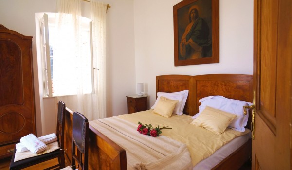 A bedroom with a wooden double bed and a wooden wardrobe in the villa Beach House Orebic by the sea