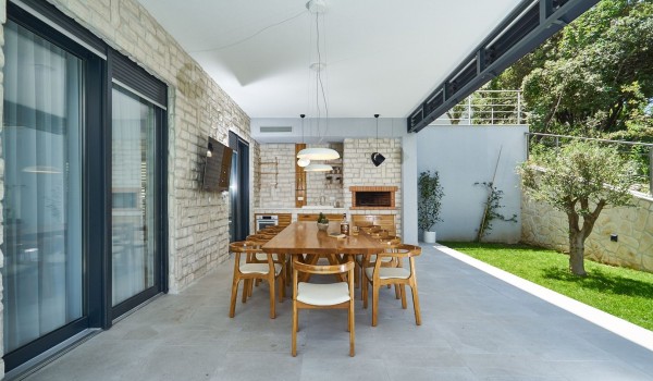 Outdoor dining table and summer kitchen on the terrace of a luxury vacation villa with concierge service near the sea