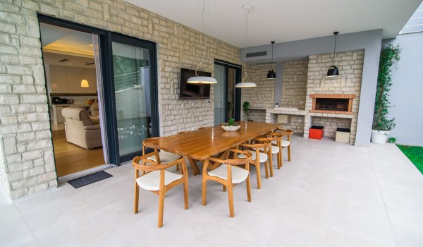 Outdoor dining table and summer kitchen on the terrace of a luxury vacation villa with concierge service near the sea