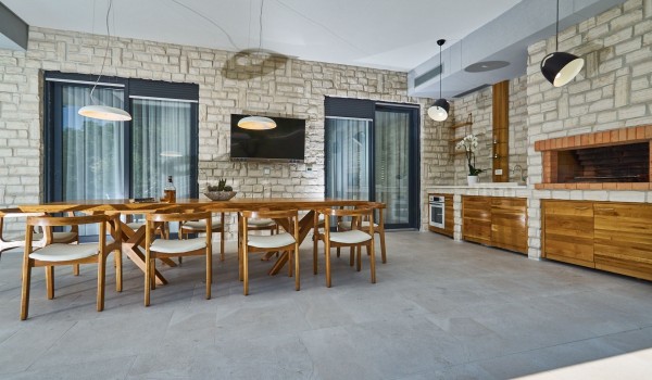 Outdoor dining table and summer kitchen on the terrace of a luxury vacation villa with concierge service near the sea