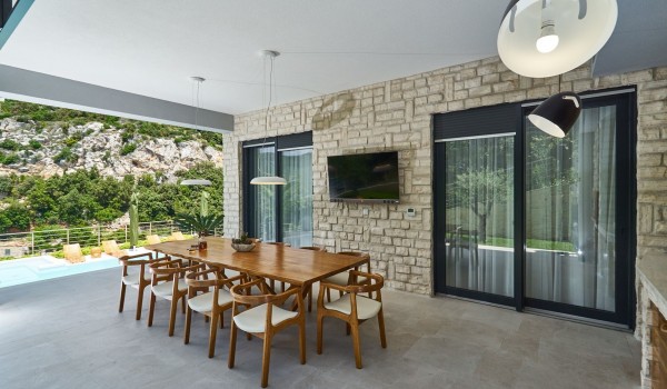 Outdoor dining table and summer kitchen on the terrace of a luxury vacation villa with concierge service near the sea