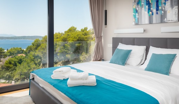 Bedroom with the king size bed and the floor-to-ceiling glass windows with the balcony overlooking the sea for vacation and rent with family and friends