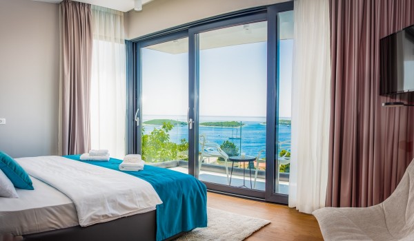 Bedroom of the luxurious villa Hvar Fantasy with the lounge chairs with the smart TV and the king size bed overlooking the sea view in Hvar