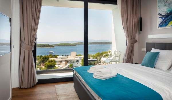 Bedroom with the king size bed and the floor-to-ceiling glass windows with the balcony overlooking the sea for vacation and rent with family and friends