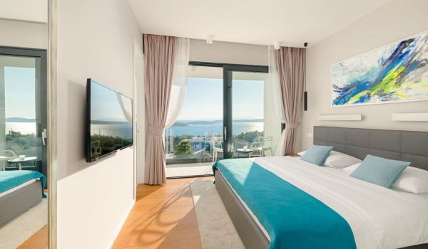 Bedroom with the king size bed and the floor-to-ceiling glass windows with the balcony overlooking the sea for vacation and rent with family and friends