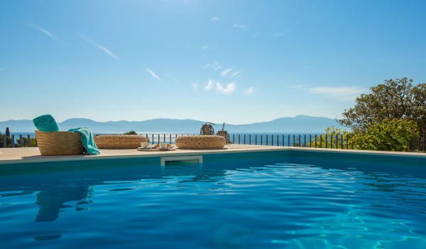 Outdoor pool near sunbathing area with sea view in pet-friendly luxury villa in Makarska for vacation and rent.