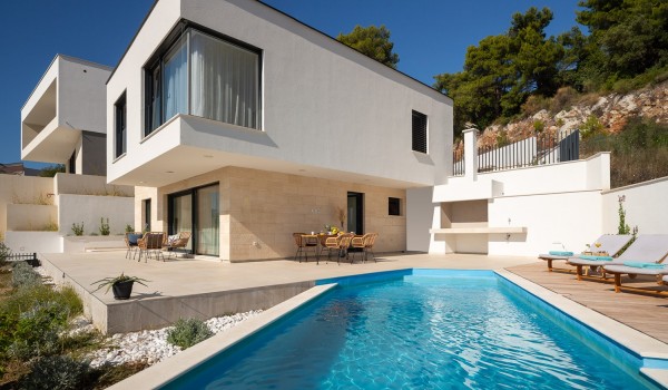 Outdoor pool near sunbathing area with sea view in pet-friendly luxury villa in Makarska for vacation and rent.