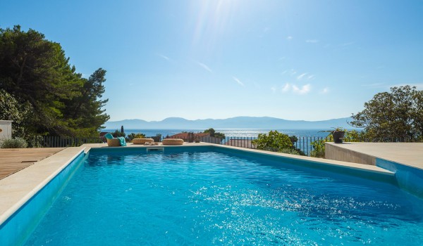 Outdoor pool near sunbathing area with sea view in pet-friendly luxury villa in Makarska for vacation and rent.