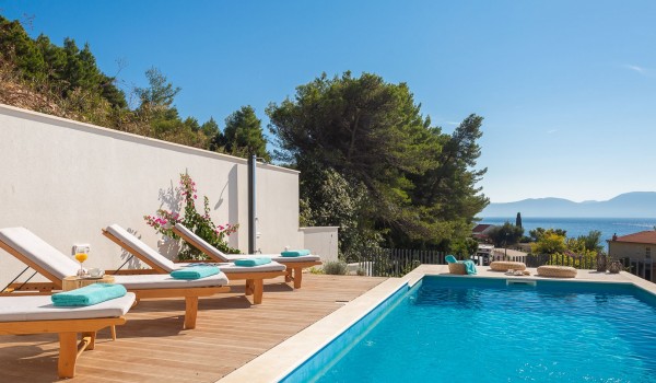 Outdoor pool near sunbathing area with sea view in pet-friendly luxury villa in Makarska for vacation and rent.