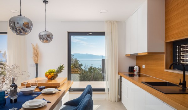 Dining table with utensils and fully equipped kitchen in Makarska luxury vila Azul with pool and sea view.