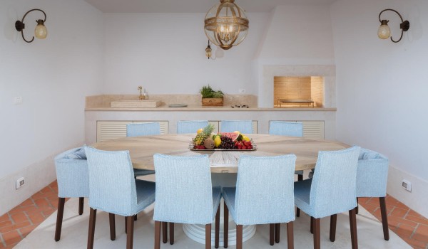 A round dining table with chairs, a kitchen with elements and an outdoor fireplace in the luxurious villa Lea in Vabriga in Istria