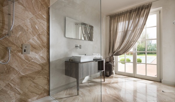A modern bathroom with a shower, sink, mirror and a view of the outdoor terrace in the luxury villa Lea in Vabriga in Istria