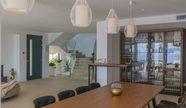 The interior design of the luxurious villa Glorious Brela in Brela with a dining table, display case with alcoholic beverages and stairs leading to the first floor