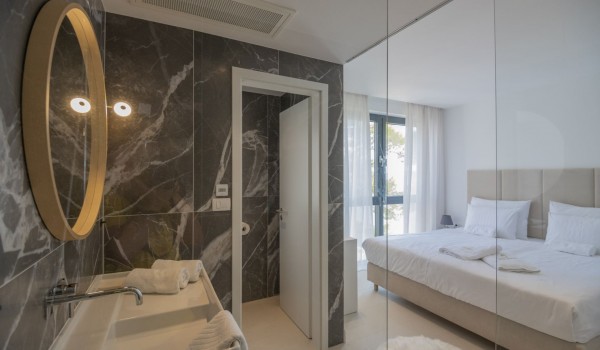 A bedroom with an en suite bathroom and a double bed in a luxury private pool villa with a private pool in Brela