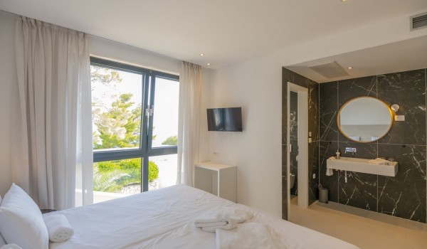 En suite bathroom and double bed with a view of the greenery and the sea in the luxurious villa Glorious Brela in Brela