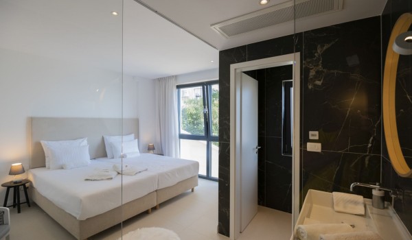 En suite bathroom with toilet, mirror and sink and a double bed in the bedroom in a luxury villa with a private pool in Brela